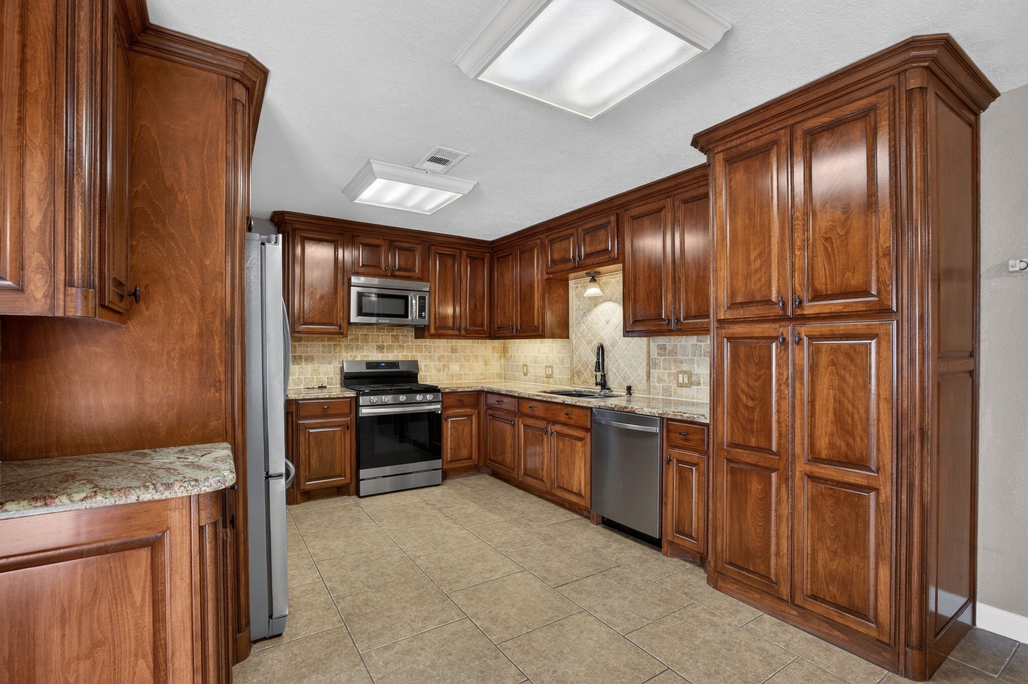 255 Gilmer Street Bridge City, TX 77611 - Photo 11 of 37 a kitchen with granite countertop stainless steel appliances and wooden cabinets