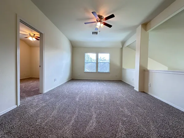 an empty room with windows and fan
