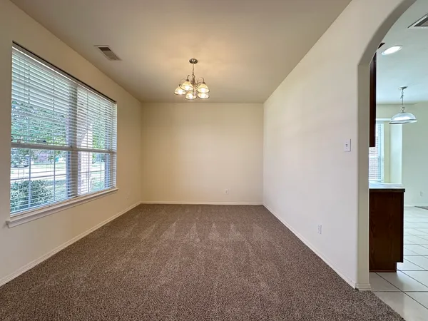 an empty room with chandelier and windows