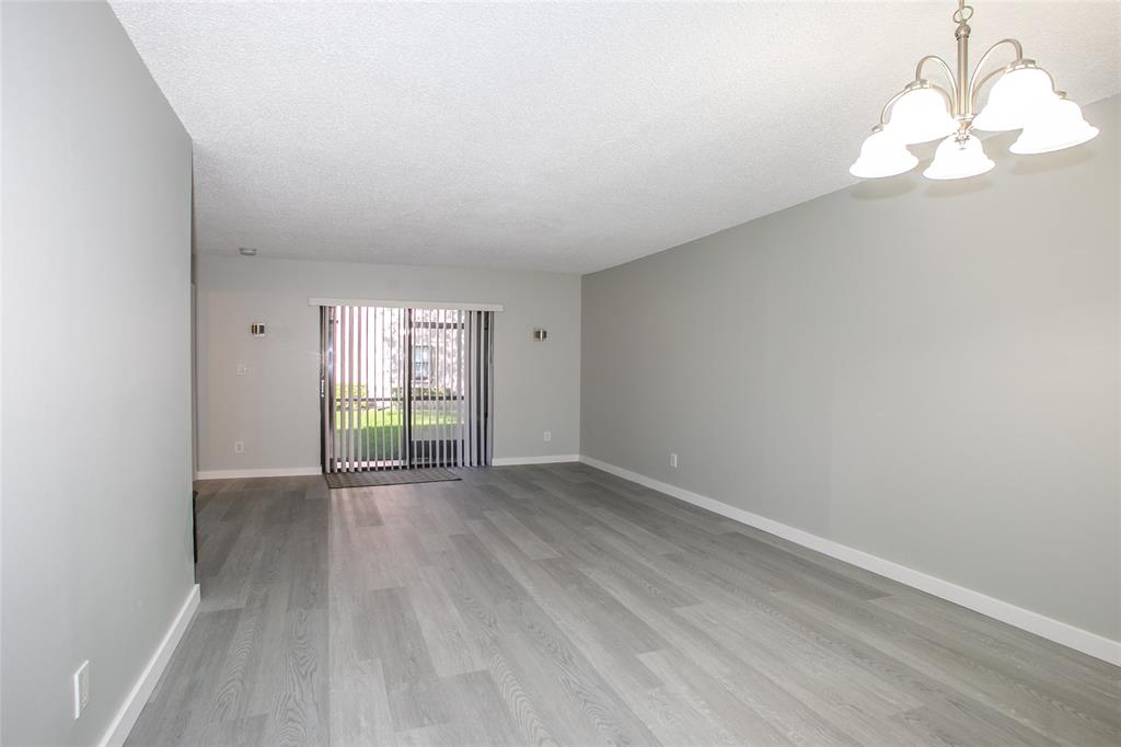10557 Northwest 10th Street, Unit 101 Pembroke Pines, FL 33026 - Photo 3 of 19 a view of an empty room with wooden floor and a window