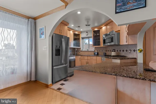 a kitchen with stainless steel appliances granite countertop a refrigerator a stove and a sink with wooden floor