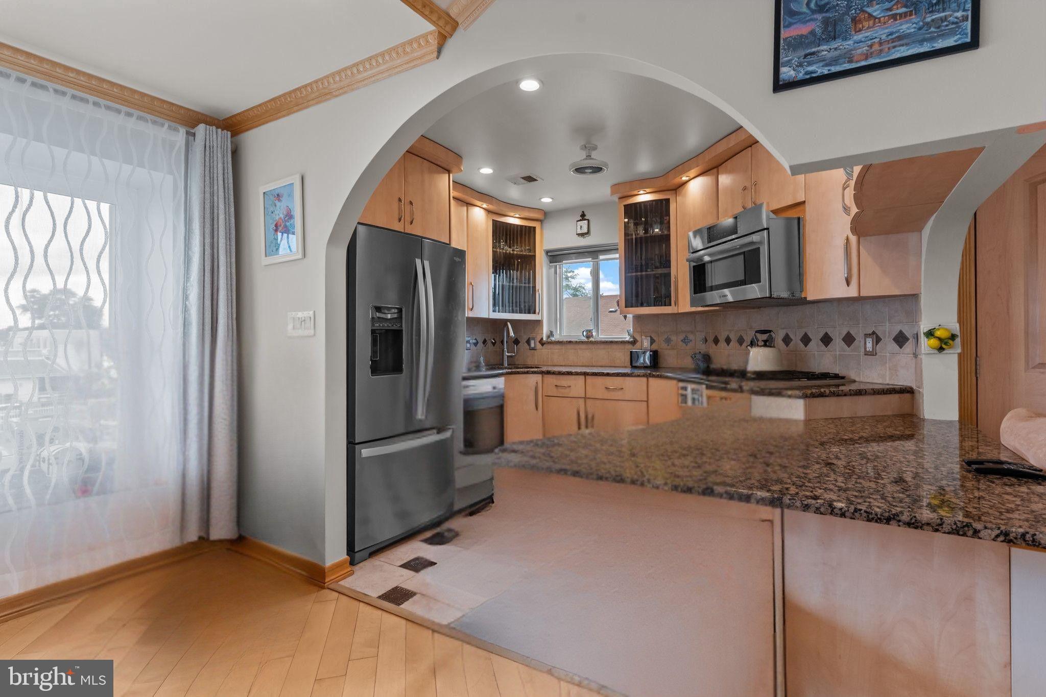 75 Bonnie Gellman Court, Unit D75 Philadelphia, PA 19114 - Photo 6 of 37 a kitchen with stainless steel appliances granite countertop a refrigerator a stove and a sink with wooden floor