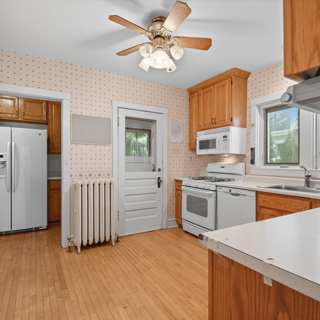 105 Dupee Place Wilmette, IL 60091 - Photo 12 of 33 a kitchen with stainless steel appliances granite countertop a stove top oven a sink a refrigerator with white cabinets and wooden floor