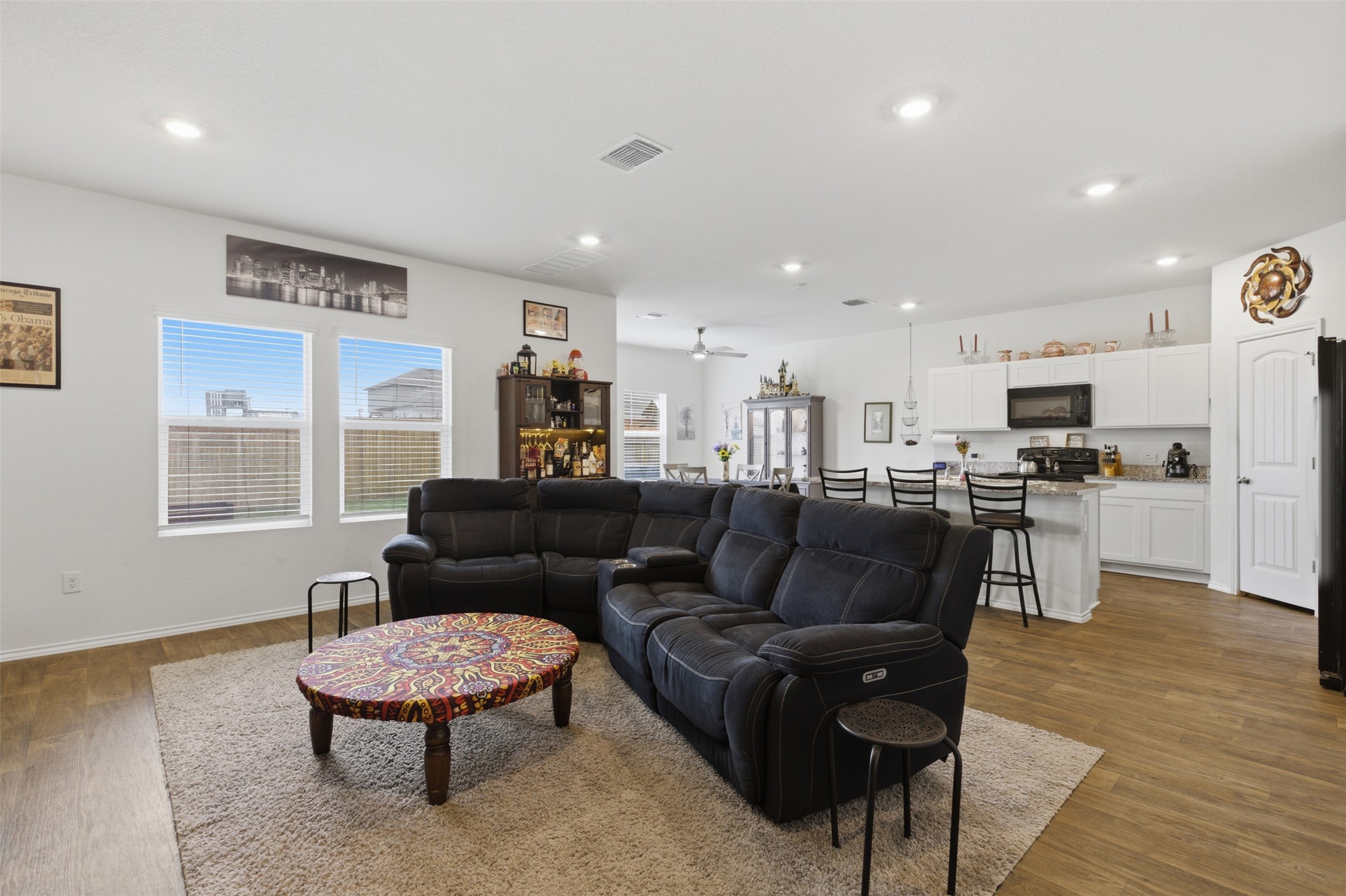 19017 Romano Drive Elgin, TX 78621 - Photo 8 of 33 Open-concept living space featuring wood-finish flooring, recessed lighting, and a kitchen with white cabinetry, a kitchen island, and stainless steel appliances