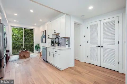a room with kitchen island a large window a sink wooden floor and furniture