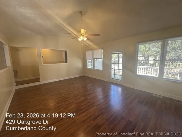 an empty room with wooden floor and windows