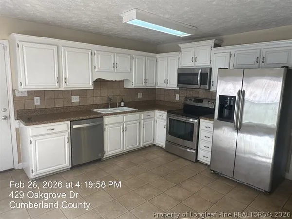 a kitchen with stainless steel appliances granite countertop a sink a stove a refrigerator with white cabinets