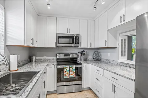 a kitchen with granite countertop white cabinets stainless steel appliances and a sink