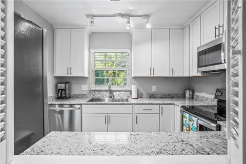 a kitchen with stainless steel appliances granite countertop a sink stove and refrigerator