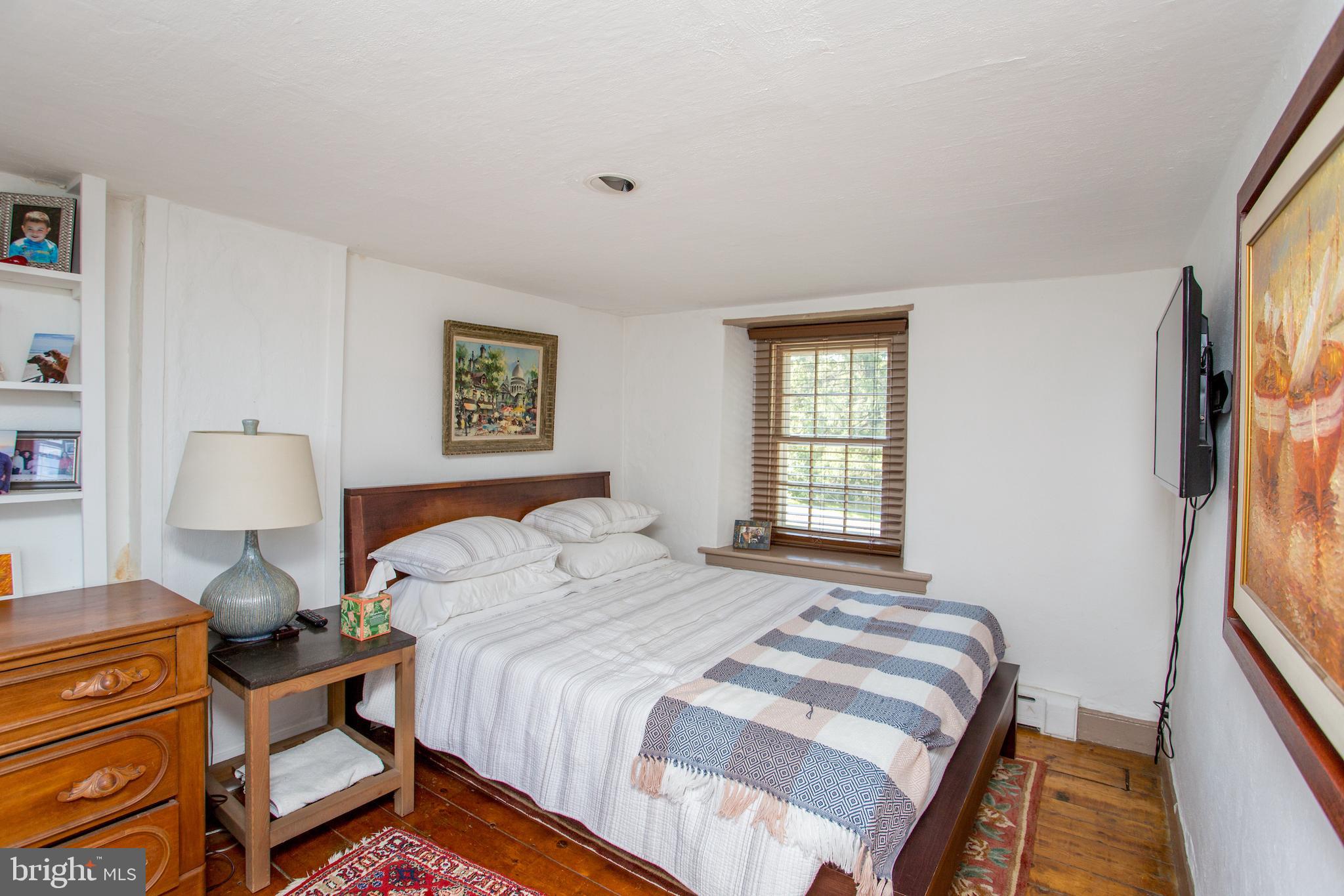3605 Windy Bush Road New Hope, PA 18938 - Photo 40 of 55 a bedroom with a bed and a lamp on dresser with a large window