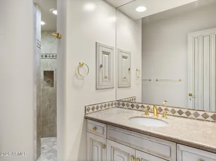 a bathroom with a granite countertop sink a mirror and shower
