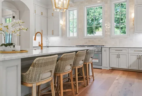 a kitchen with stainless steel appliances granite countertop a table chairs sink and window