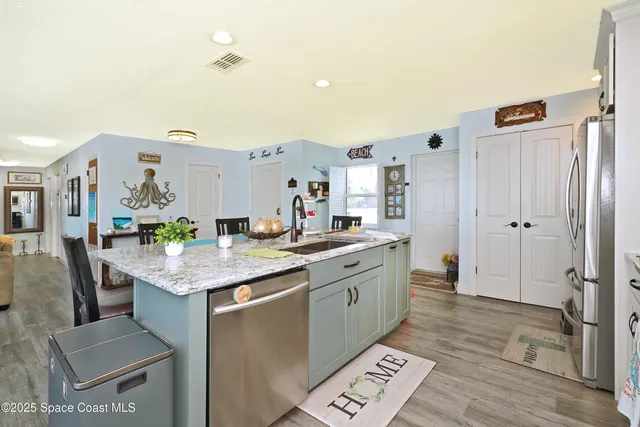 a kitchen with granite countertop a sink stainless steel appliances and white cabinets