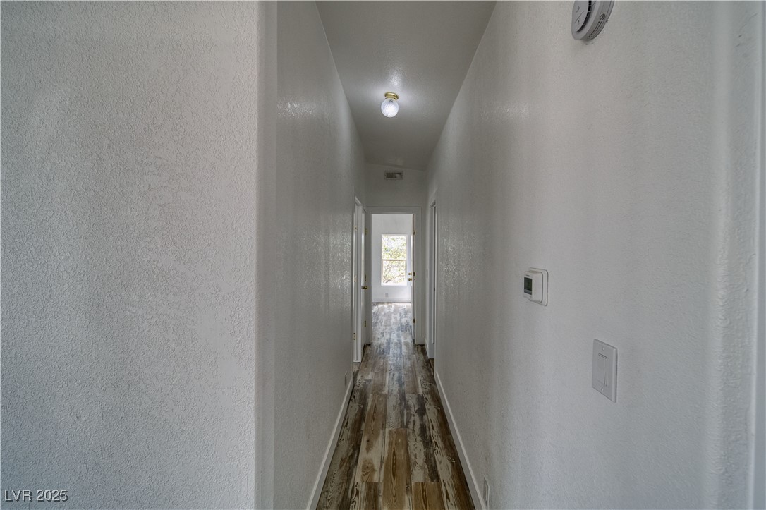 1340 South Adams Road Pahrump, NV 89048 - Photo 11 of 31 Corridor with wood finished floors and a textured wall