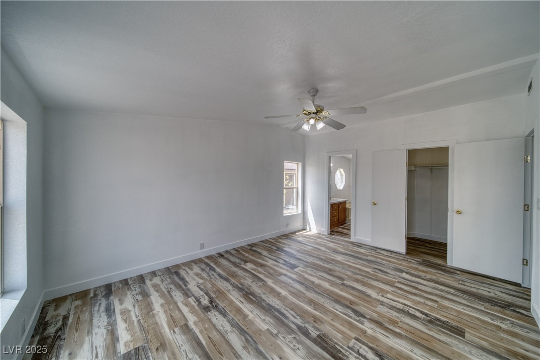 1340 South Adams Road Pahrump, NV 89048 - Photo 14 of 31 Unfurnished bedroom with wood finished floors, ceiling fan, ensuite bath, and a walk in closet