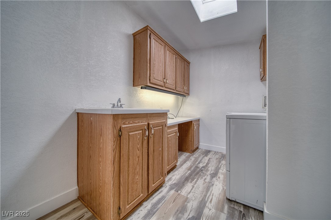 1340 South Adams Road Pahrump, NV 89048 - Photo 23 of 31 Laundry area with washer / dryer, a textured wall, a skylight, light wood-type flooring, and cabinet space