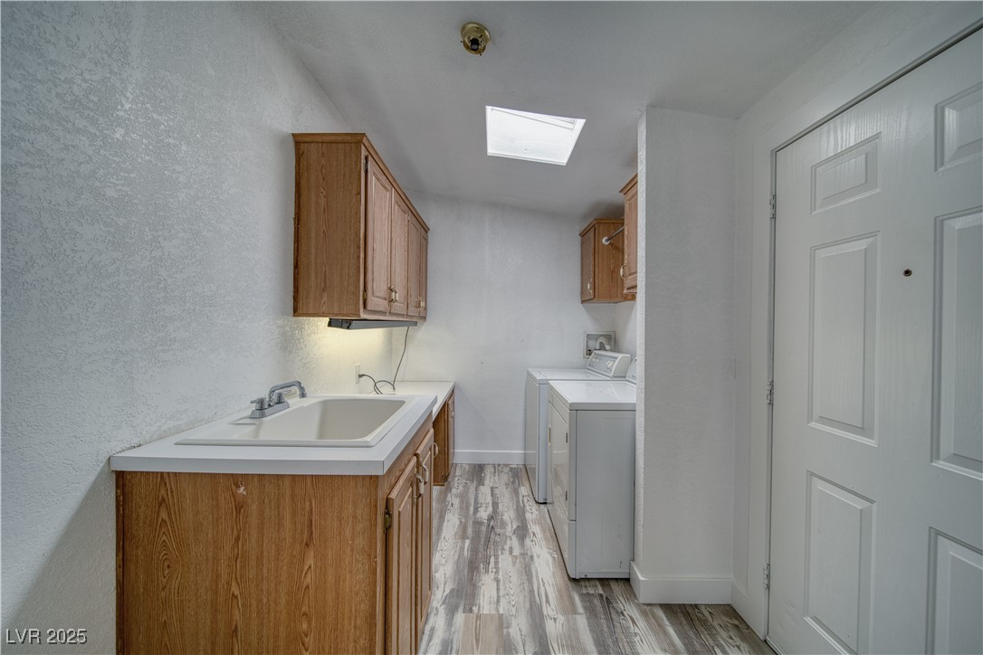 1340 South Adams Road Pahrump, NV 89048 - Photo 24 of 31 Laundry room featuring cabinet space, independent washer and dryer, light wood-style flooring, a textured wall, and a skylight