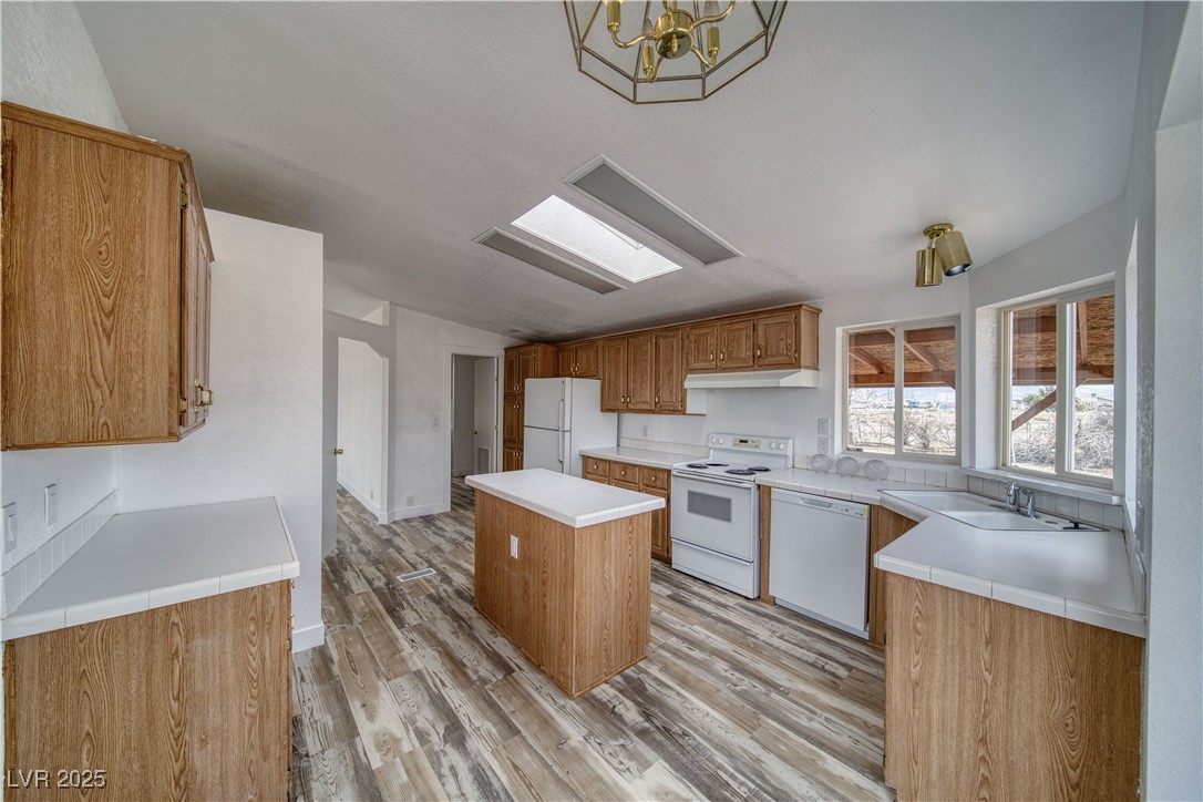 1340 South Adams Road Pahrump, NV 89048 - Photo 7 of 31 Kitchen featuring a kitchen island, white appliances, light wood-style floors, light countertops, and under cabinet range hood