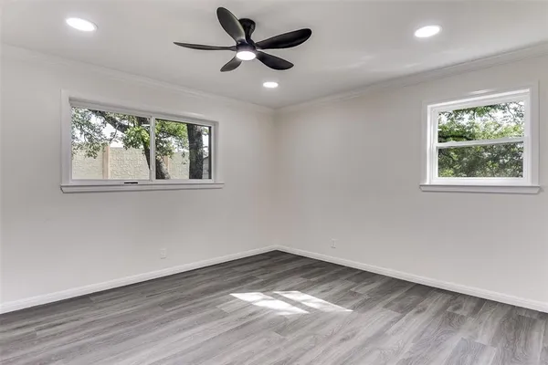 a view of empty room with wooden floor and fan