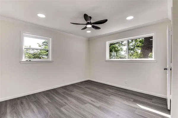 a view of empty room with wooden floor and fan