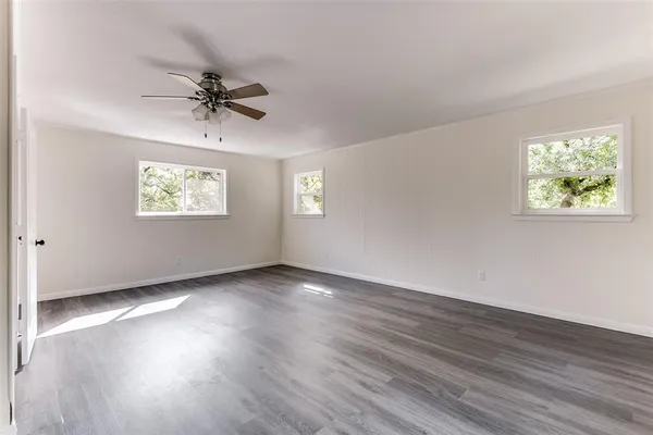a view of an empty room with wooden floor and window