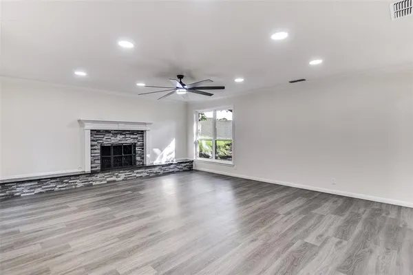 an empty room with wooden floor fireplace and windows