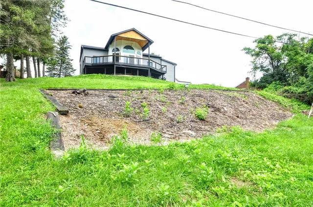 a view of a big house with a big yard and large trees