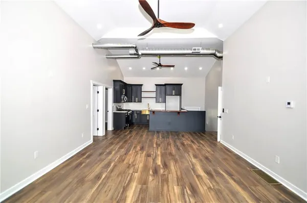 a kitchen with stainless steel appliances granite countertop a refrigerator a sink dishwasher a stove and black cabinets with wooden floor