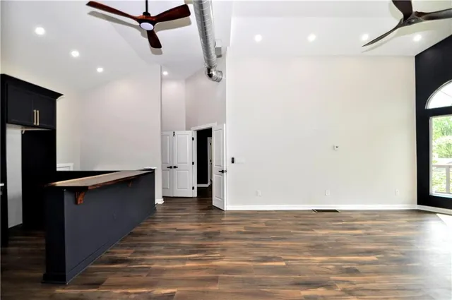 an empty room with wooden floor fan and windows