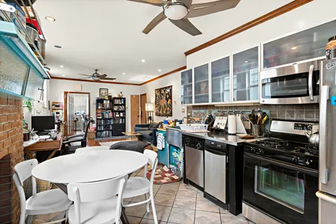 a kitchen with stainless steel appliances a stove a sink dishwasher a dining table and chairs with wooden floor
