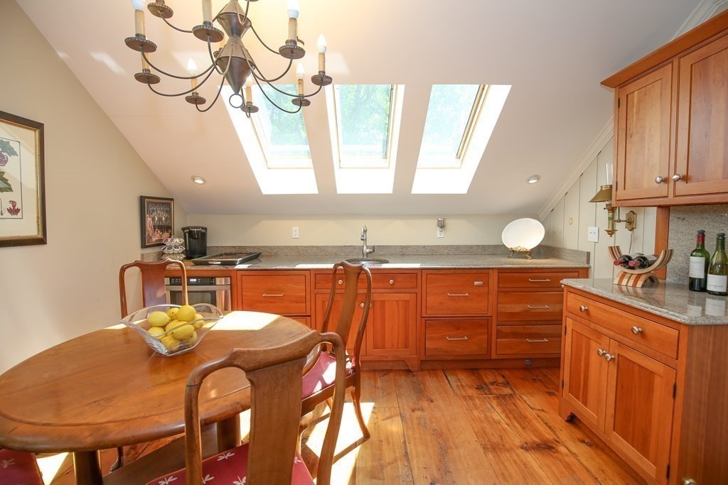 21 Rolfe's Lane Newbury, MA 01951 - Photo 23 of 42 a kitchen with stainless steel appliances kitchen island granite countertop a table chairs in it and wooden floors