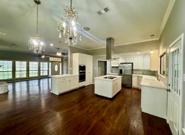 a kitchen with stainless steel appliances a stove top oven a refrigerator a dining table and chairs with wooden floor