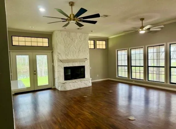 a view of an empty room with wooden floor fireplace and a window