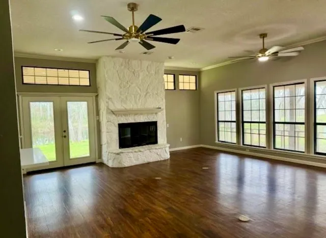 a view of an empty room with wooden floor fireplace and a window