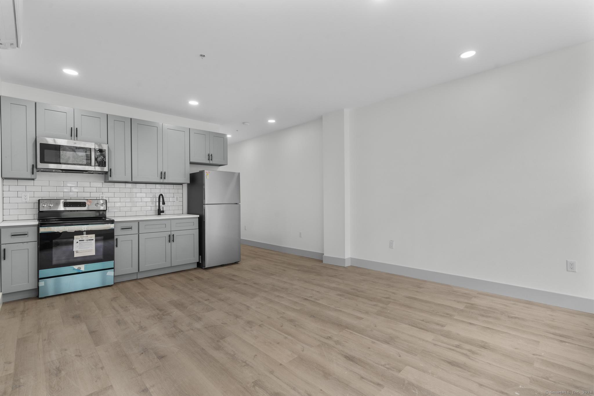 111 Bank Street, Unit 2B Waterbury, CT 06702 - Photo 2 of 15 a kitchen with stainless steel appliances a refrigerator and a stove top oven