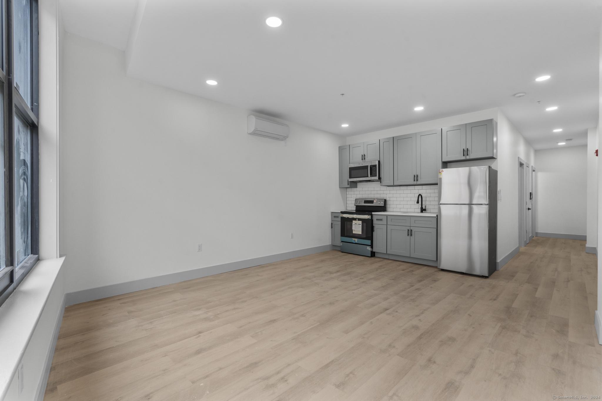 111 Bank Street, Unit 2B Waterbury, CT 06702 - Photo 3 of 15 a view of kitchen with refrigerator cabinets and wooden floor