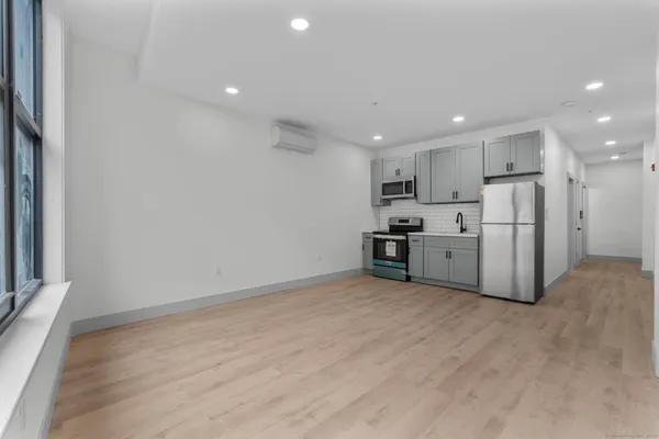 a view of an empty room with a window and wooden floor