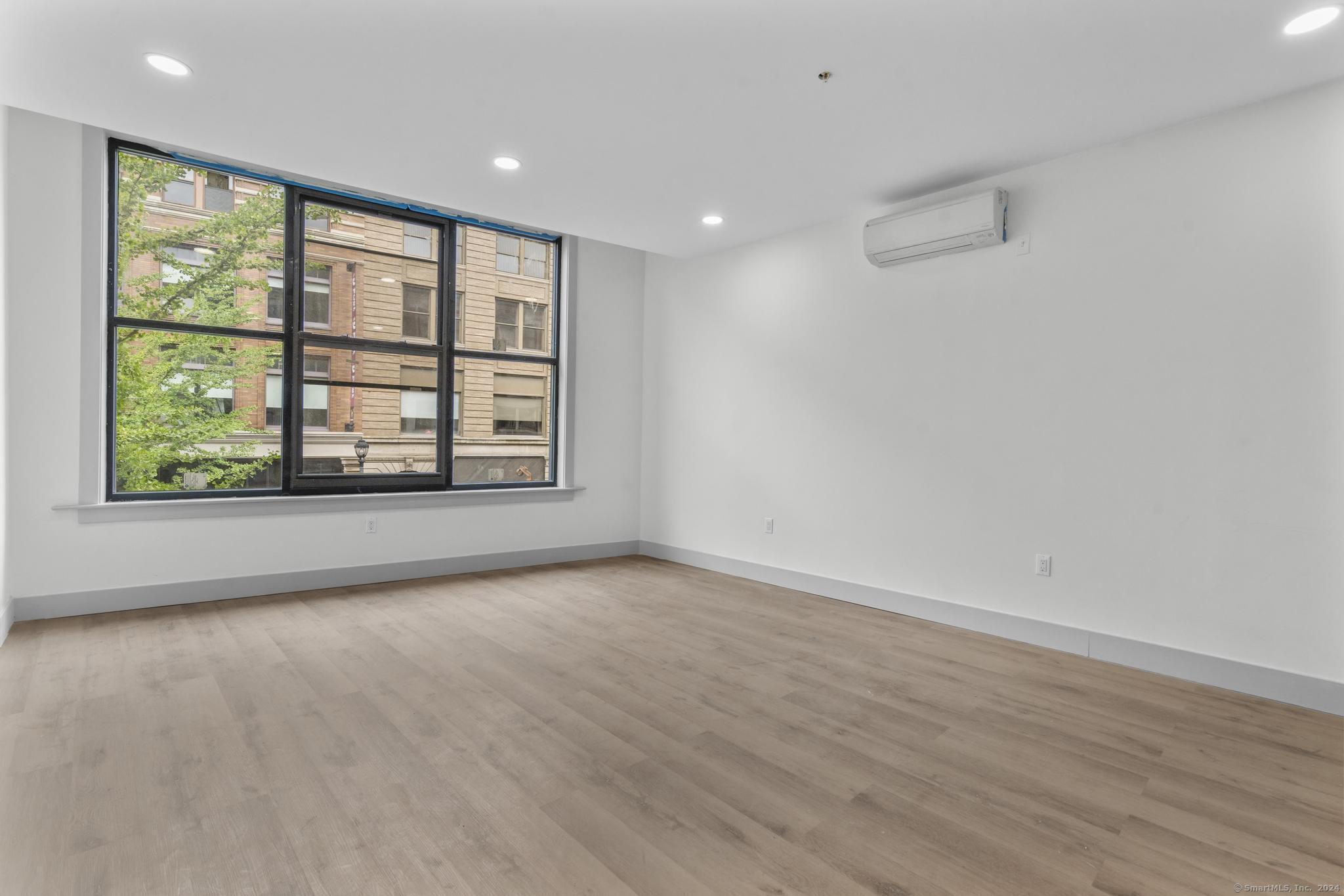 111 Bank Street, Unit 2B Waterbury, CT 06702 - Photo 5 of 15 a view of an empty room with a window and wooden floor