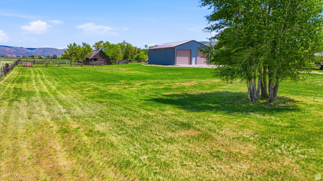 4540 Dingle Road Dingle, ID 83233 - Photo 18 of 22 Expansive green space featuring a large outbuilding with multiple garage doors, a rustic wooden structure, and scattered trees