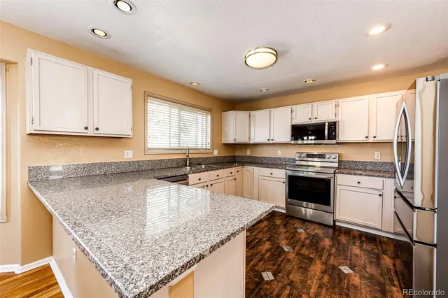 a kitchen with stainless steel appliances granite countertop a sink stove and refrigerator