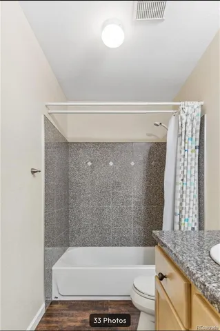 a bathroom with a granite countertop bathtub shower sink vanity and toilet