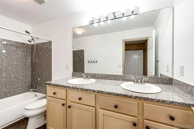 a bathroom with a granite countertop sink mirror vanity and toilet