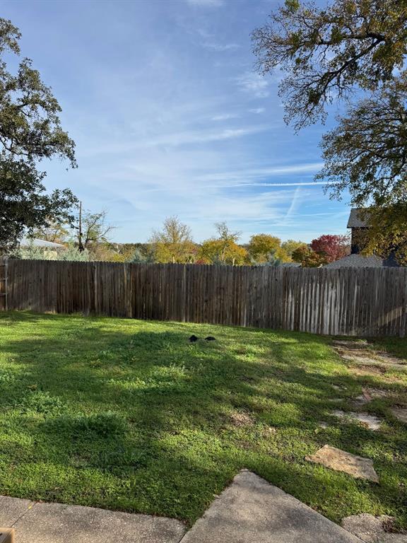 9551 Lechner Road, Unit G Fort Worth, TX 76179 - Photo 5 of 15 Expansive backyard featuring a wood privacy fence, concrete patio area, and mature trees providing shade