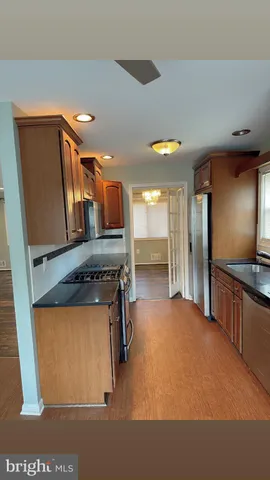 a kitchen with stainless steel appliances granite countertop a refrigerator a stove and a sink with wooden floor