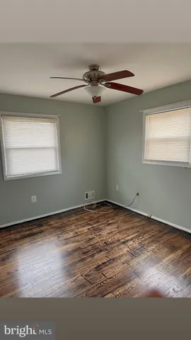 a view of a room with a ceiling fan and hardwood floor