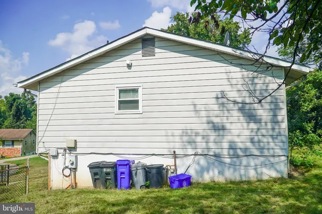 a view of a white house with a small yard and large tree