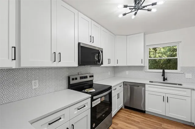 a kitchen with cabinets stainless steel appliances a sink and a window