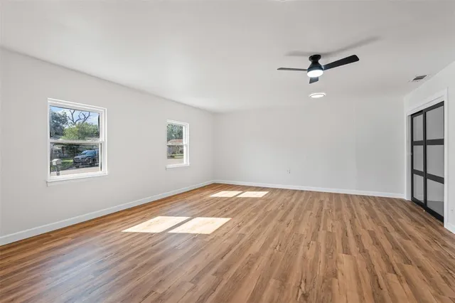 a view of empty room with wooden floor and fan