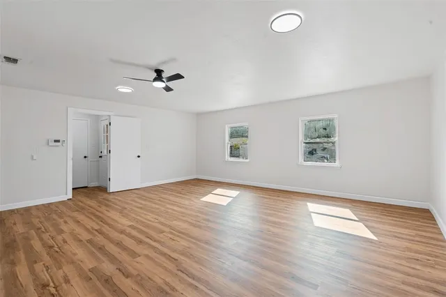 an empty room with wooden floor and windows