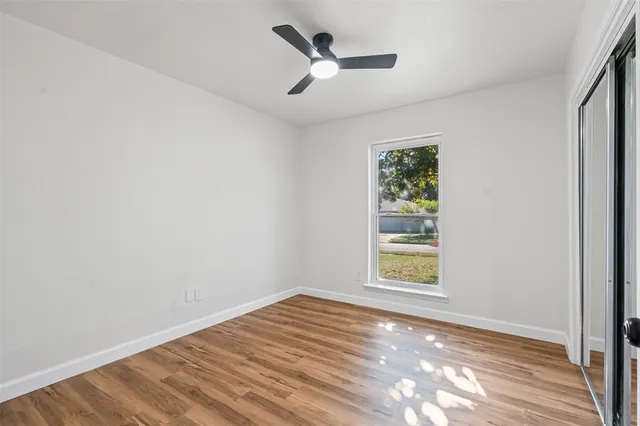 a view of empty room with wooden floor and fan